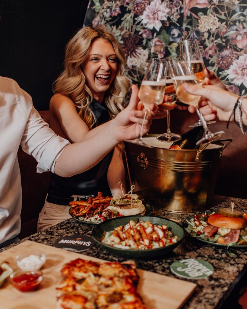 Friends toasting with prosecco over bottomless brunch food at Oriels Exeter